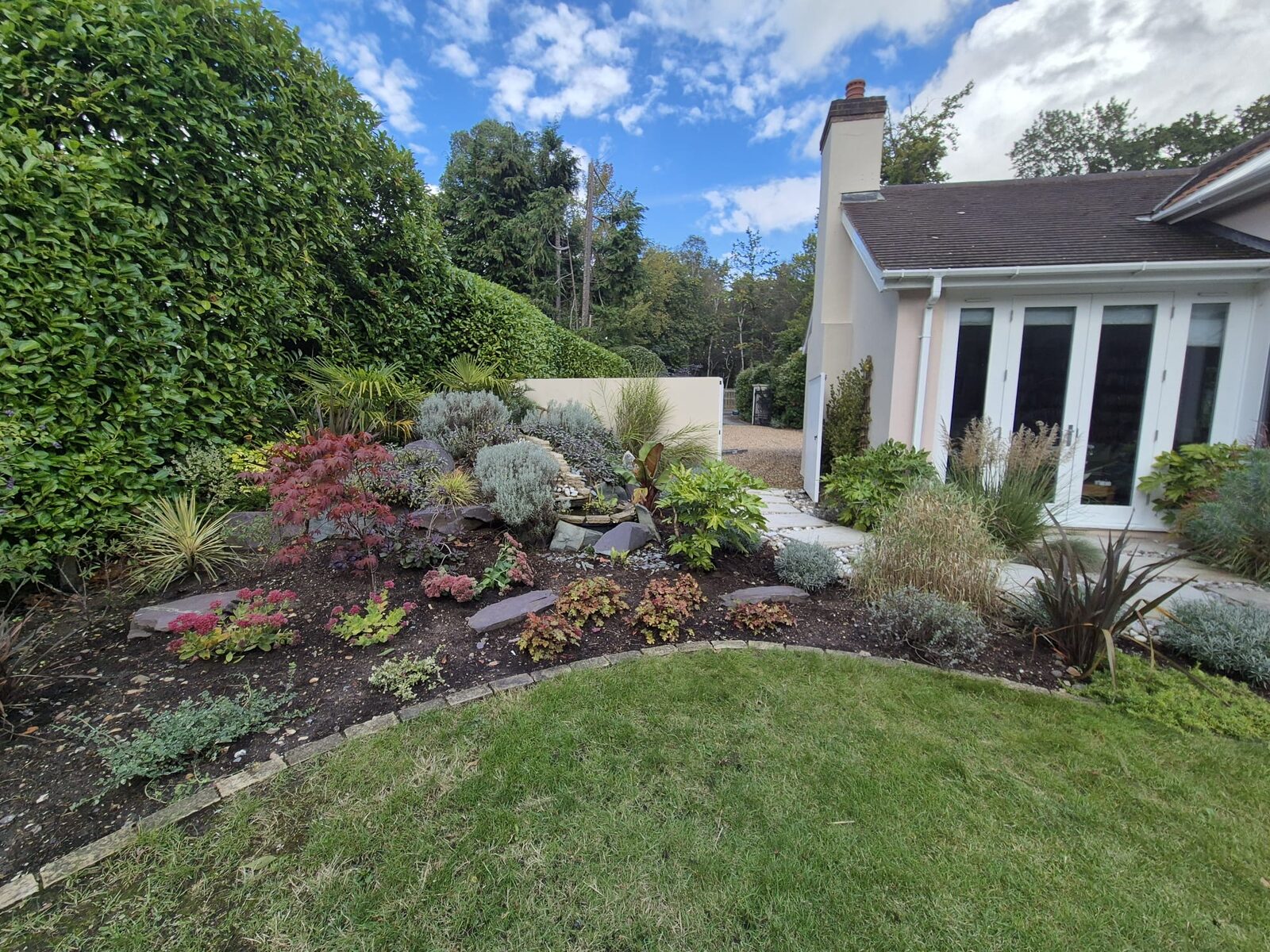 Landscaped rockery border with Japanese maple, ornamental grasses and a small water feature