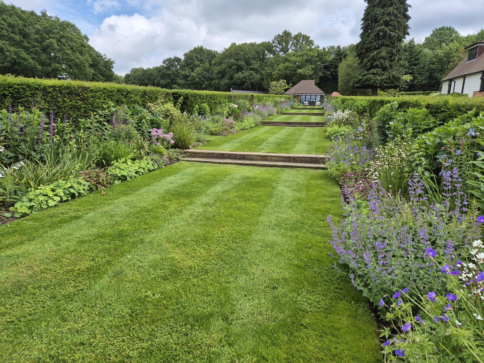 Long striped lawn with stone steps and flowering borders